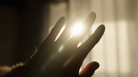 male hand playing with sunlight glare coming through windowの写真素材
