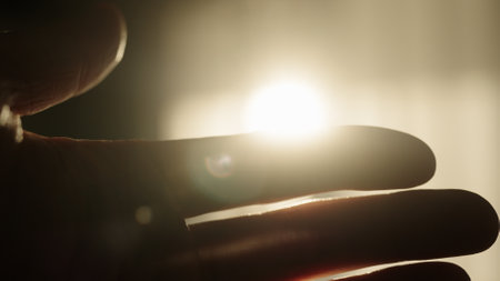 male hand playing with sunlight glare coming through windowの写真素材