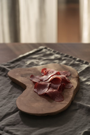 Dried pastrami slices on a wooden board with natural lightの写真素材