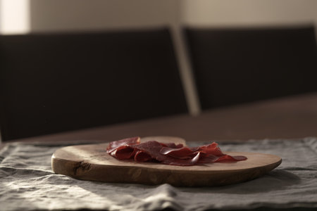 Dried pastrami slices on a wooden board with natural lightの写真素材