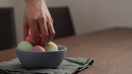 Man hand put easter egg in a bowl on walnut table