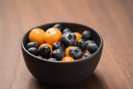 Blueberries with physalis in a bowl on wood tableの写真素材