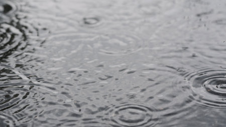 closeup of summer heavy rain drops falling into puddles on asphaltの写真素材