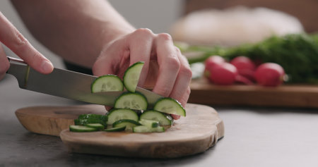 man slicing fresh cucumber on olive board side viewの写真素材
