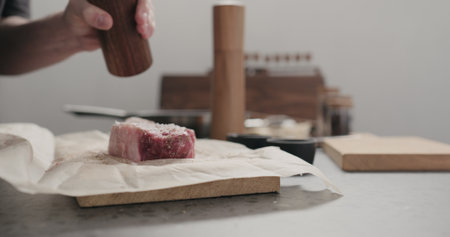 man grinding pepper on new york steak on countertopの写真素材