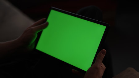 Man at home lying on a couch with tablet pc with green screenの写真素材