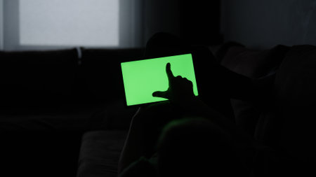 Man at home lying on a couch with tablet pc with green screen