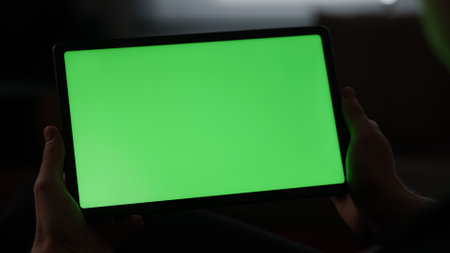 Man at home lying on a couch with tablet pc with green screenの写真素材