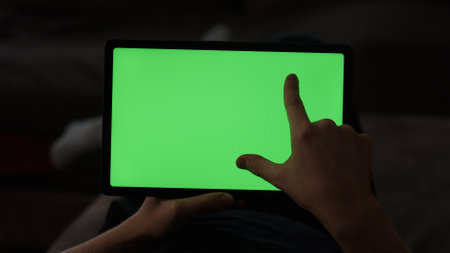 Man at home lying on a couch with tablet pc with green screenの写真素材