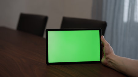 Man at home using tablet pc with green screen while sitting at the tableの写真素材