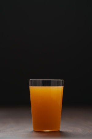 Fresh orange juice in thin glass on wooden table with copy spaceの写真素材