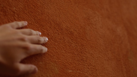 closeup man hand touching terracotta wall