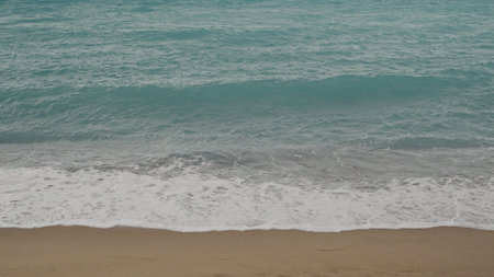 Clear blue waves with strong wind on a sandy empty beach in Cannes in spring