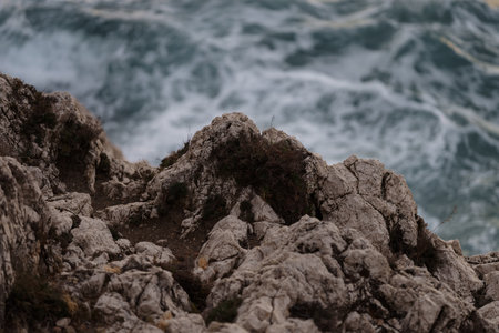 Sea waves crashing against the rocks of mediterranean shore during sunset