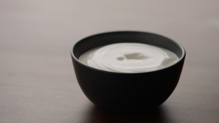 organic yogurt in black bowl on wood tableの写真素材