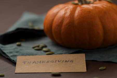 Orange pumpkin with seeds on wood table with thanksgiving paper cardの写真素材