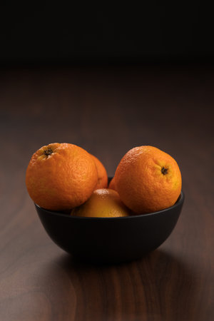 Fresh tangerines in a bowl on a wood tableの写真素材