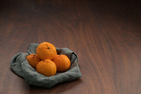Organic tangerines on a linen napkin on a wood tableの写真素材