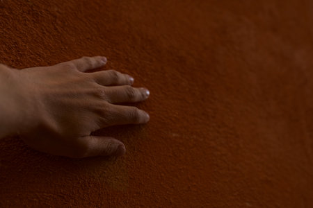 closeup man hand touching old terracotta wallの写真素材