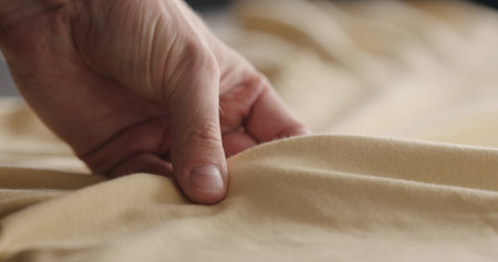 man touching yellow cotton clothes closeupの写真素材
