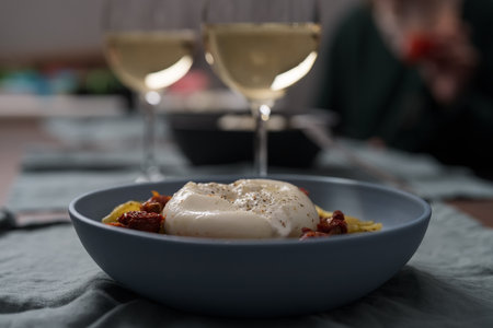 Pesto conchiglie with sundried tomatoes and burrata cheese served in blue bowlの写真素材