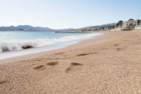 Footsteps on a sand beach of South France during spring with sea wavesの写真素材