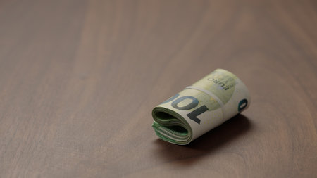 Roll of hundred euro bills on walnut table   shotの写真素材