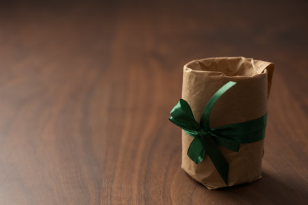 Brown paper gift with green ribbon on walnut wood table with copy spaceの写真素材