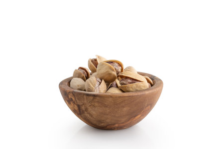 salted pistachios in wood bowl isolated on white backgroundの写真素材
