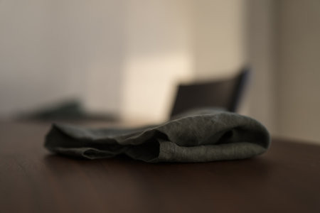 Dark green linen napkin on walnut table indoor with natural window lightの写真素材