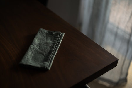Dark green linen napkin on walnut table indoor with natural window lightの写真素材
