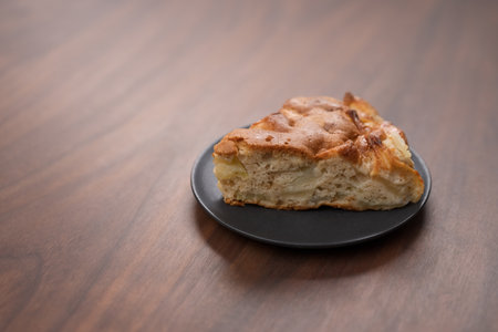 A piece of charlotte apple pie on a saucer on walnut tableの写真素材