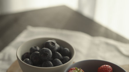 fresh blueberries and strawberries in ceramic bowls with natural lightの写真素材