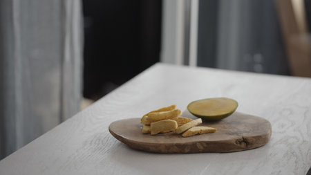 Sublimated mango next to fresh mango on olive board on white oak tableの写真素材