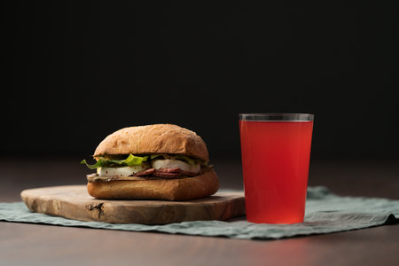 Roast beef and mozzarella sandwich with ciabatta bun on olive board with red lemonadeの写真素材