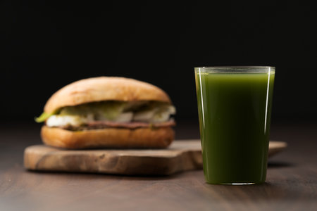 Roast beef and mozzarella sandwich with ciabatta bun on olive board with fresh green drinkの写真素材