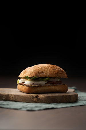 Roast beef and mozzarella sandwich with ciabatta bun on olive boardの写真素材