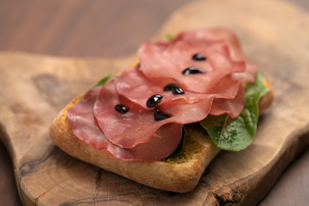 Sandwich with bresaola, pesto and balsamic on olive boardの写真素材