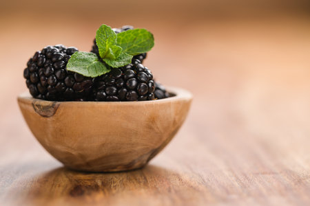 fresh blackberries in wood bowl on wooden table with mint leavesの写真素材