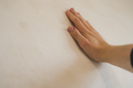 closeup young man hand touching plastered wallの写真素材