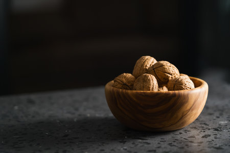 inshell walnuts in olive wood bowl on terrazzo countertopの写真素材