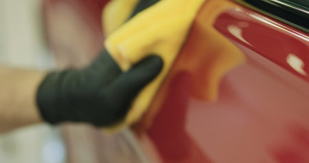 closeup of wiping red car with microfiber cloth