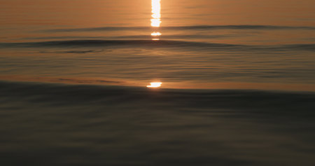 small waves on a beach at sunset