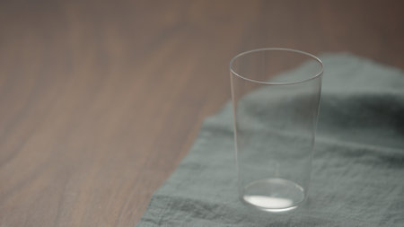 empty tumbler glass on linen clothの写真素材