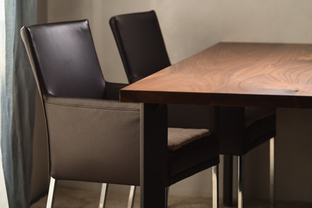 Minimalist kitchen interior with walnut dining table and leather arm chairsの写真素材