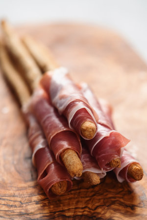 Grissini with prosciutto on olive wood boardの写真素材