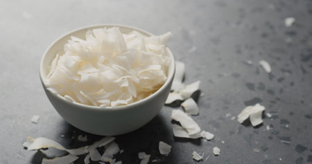 coconut chips in white bowl on terrazzo surface