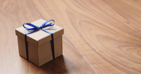 eco friendly paper gift box with blue ribbon on walnut table with copy spaceの写真素材