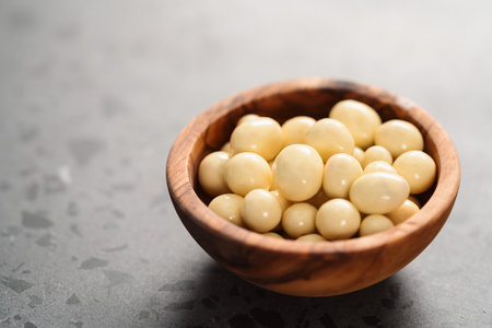 White chocolate or yogurt dragee with berries in wood bowl on concrete backgroundの写真素材