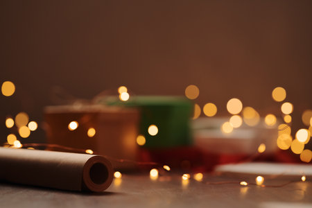 Gift boxes and festive packaging with christmas light on a table closeupの写真素材